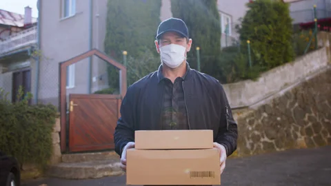 Delivery man courier with face mask delivering parcel boxes in town. Stock Footage 132216744