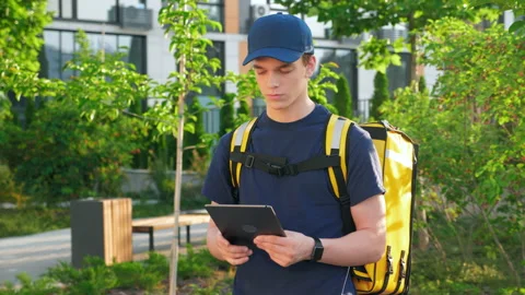 Delivery man courier with thermal backpack uses tablet confirm client order Stock Footage 156485910