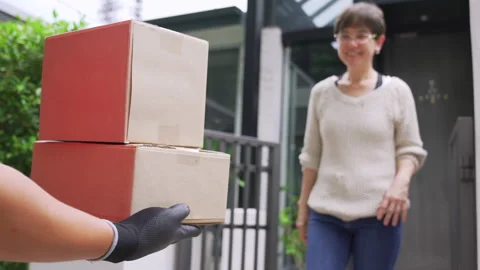 Delivery man delivering parcels to the customer at home. Stockbeeldmateriaal 138287513
