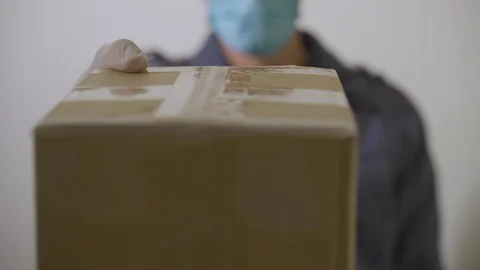 Delivery man hands package or parcel wearing gloves and face mask Stock Footage 130066382