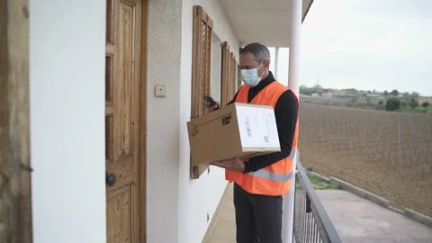 Delivery man with mask delivers package to customer. Stock Footage 149480040