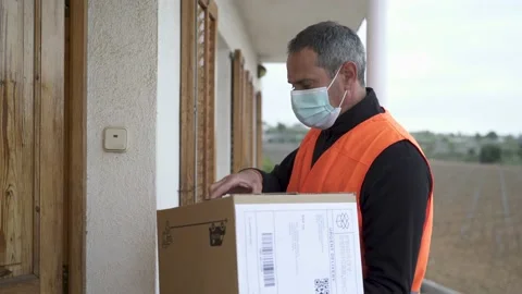 Delivery man with mask delivers package to customer. 库存影片 149480089