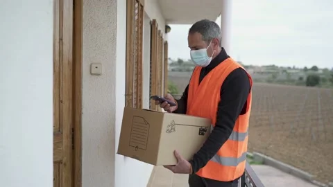 Delivery man with mask delivers package to customer. 库存影片 149480145