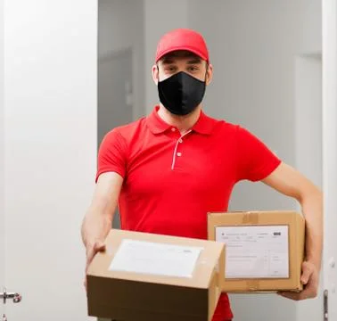 Delivery man in mask with parcel boxes 스톡 사진