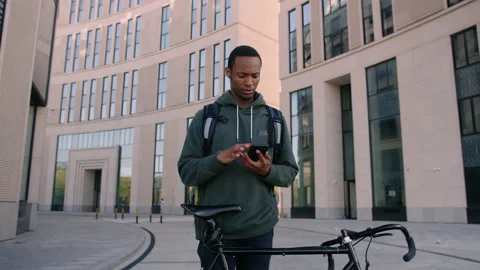 Delivery man with a mobile phone points his finger at the delivery building Stock Footage 222893196