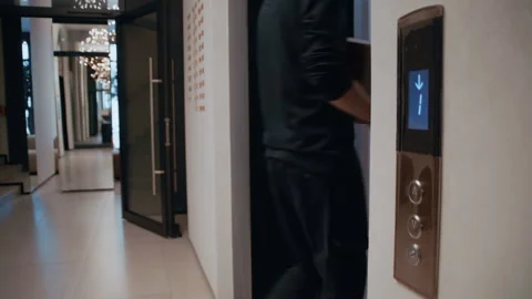 Delivery man with a package calling the elevator Stock-Footage 322512810