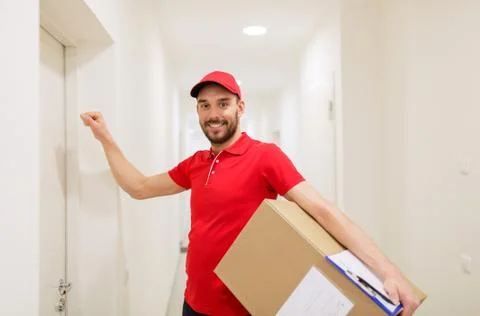 Delivery man with parcel box knocking on door 库存照片
