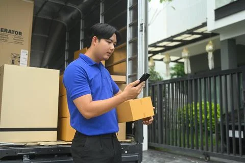 Delivery man with parcel box using mobile phone near his van. Shipping and Stock Photos