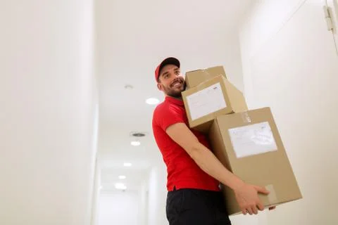 Delivery man with parcel boxes in corridor Foto stock