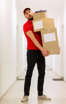 Delivery man with parcel boxes in corridor Foto stock