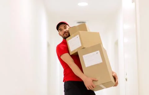 Delivery man with parcel boxes in corridor Foto stock