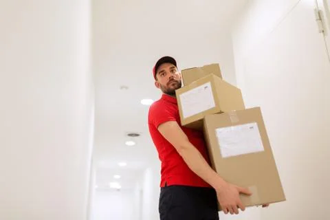 Delivery man with parcel boxes in corridor Foto stock