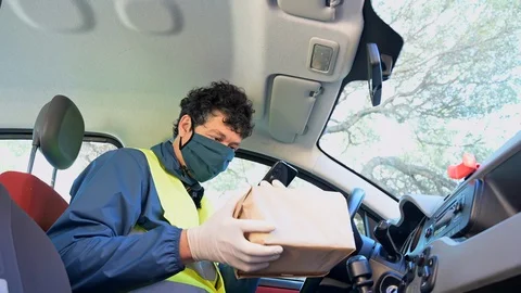 Delivery man with parcel  in the car checks the delivery address Stock Footage 129059471