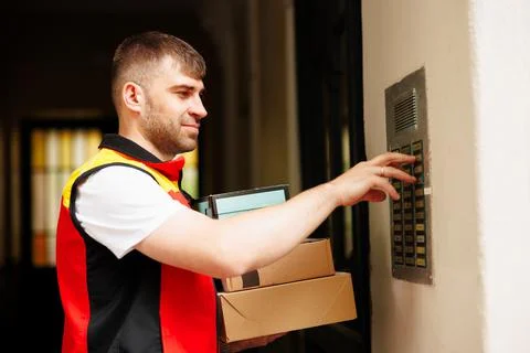 Delivery man pressing button of intercom down the street 写真素材