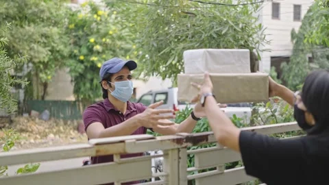 Delivery man with protective mask on face handing over parcel to lady customer 스톡 동영상 167000790
