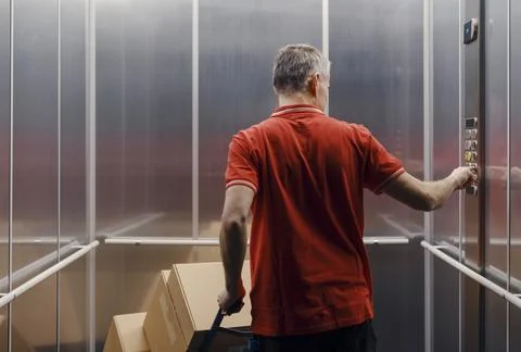 Delivery man pushing a button in the elevator Stock Photos