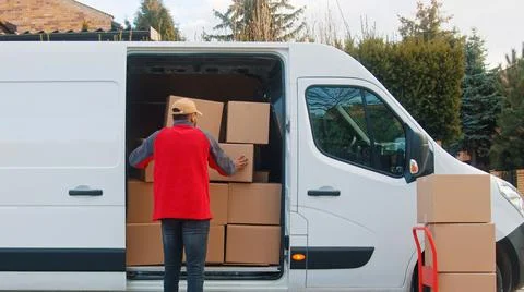 Delivery man putting parcel into the van. Delivery during covid outbreak Stock Photos