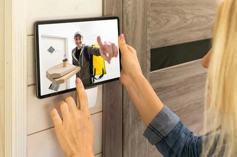 Delivery man ringing door bell on cctv secure camera system on tablet app Stock Photos