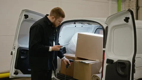 Delivery Man Scanning Cardboard Boxes in Van Using Barcode Scanner Stock Footage 340283228