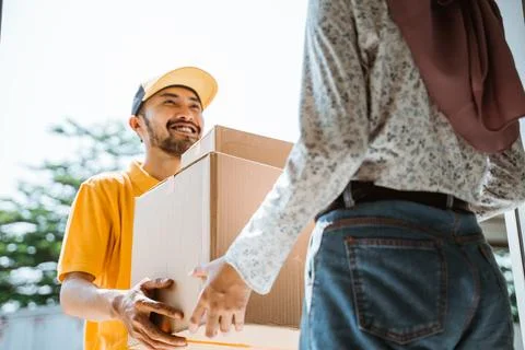 Delivery man smiling friendly while delivering package boxes to customers Stock Photos