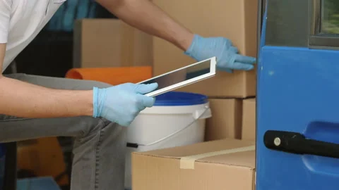 Delivery man with a tablet checks his cargo count, closeup Stock Footage 130580814