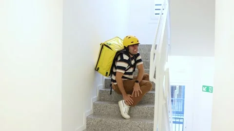 Delivery man with thermal backpack suffering ankle injury on stairs Stock Footage 318096132