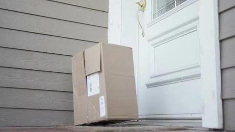 Delivery Man Throws Package on the Doorstep of a House Stockbeeldmateriaal 195589019