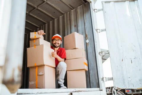 Delivery man with thumbs up working unloading boxes from containers Stock Photos