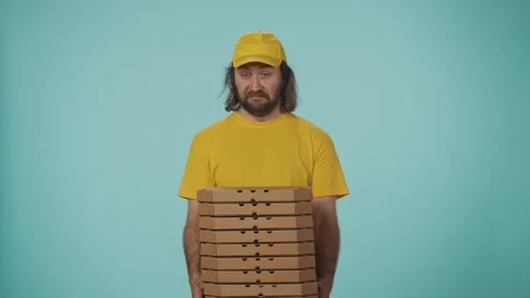 Delivery man in uniform posing at the camera, holding a big stack of pizza boxes Video stock 248771292