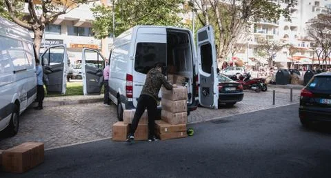 Delivery Man unloading boxes from his truck in a shopping street of Albufeira Stock Photos