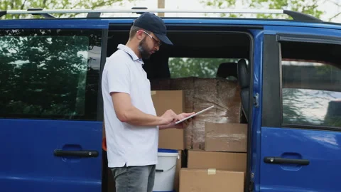 A delivery man uses a tablet near the van Stock Footage 276963344
