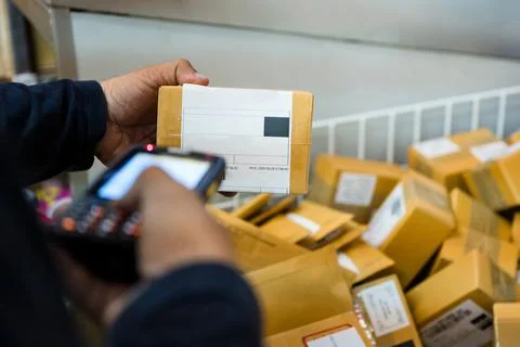 Delivery man using laser scanner scanning parcel cardboard box in distributio 写真素材