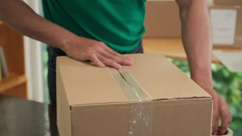 Delivery Man Using Tape to Seal Parcel and Putting Postage Stamp Stock Footage 244637209