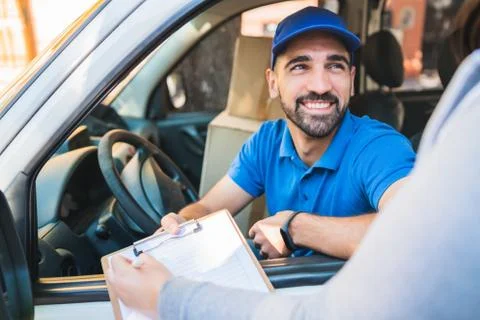 Delivery man in van while customer sign in clipboard. Stock Photos