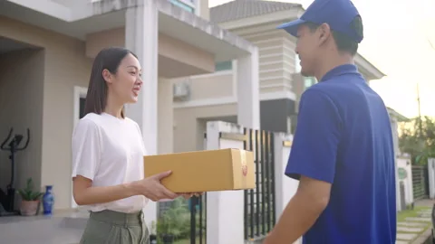 Delivery man wearing blue uniform sending a cardboard box to customer. Video stock 221574423