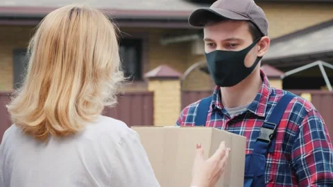 Delivery man wearing protective face mask giving cardboard box to female cu.. Stock Footage 334590457