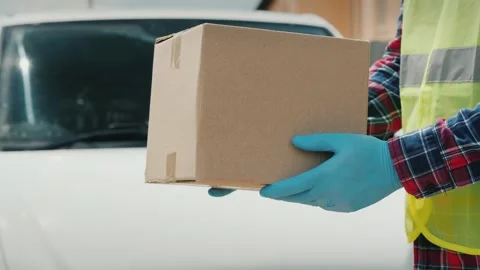 Delivery man wearing protective gloves holding cardboard box in front of wh.. Stock Footage 334828811