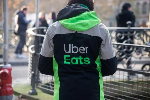 Delivery man wearing an Uber eats vest standing in the street Stock Photos