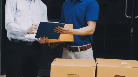 Delivery man wearing uniform unloading parcel Stock Footage 303457789