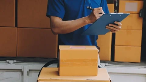 Delivery man wearing uniform unloading parcel Stock Footage 303457791
