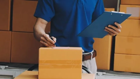 Delivery man wearing uniform unloading parcel Stock Footage 303457792