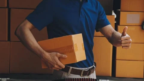 Delivery man wearing uniform unloading parcel Stock Footage 303457794