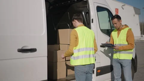 Delivery man at work, one arranging boxes in the van while other checks the list Stock Footage 263895266