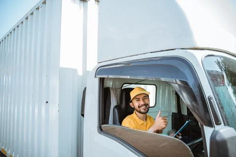 Delivery man in yellow uniform with thumbs up while driving Stock Photos