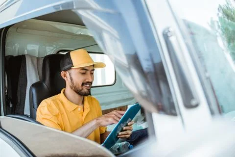 Delivery man in yellow uniform using clipboard before delivering goods Stock Photos