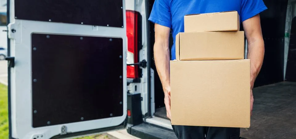 Delivery person holding stack of boxes in front on van background. copy space Foto stock