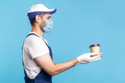 Delivery service. Side view, friendly happy courier man in overalls offering  Stock Photos