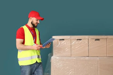 Delivery service worker checking order details on clipboard next to stacked c Stock Photos