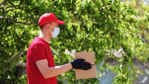 A delivery service worker hands over cardboard boxes in medical  gloves . Stock Footage 129549018