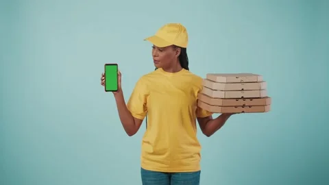 Delivery woman in uniform holding stack of pizza boxes and smartphone Video stock 248749345